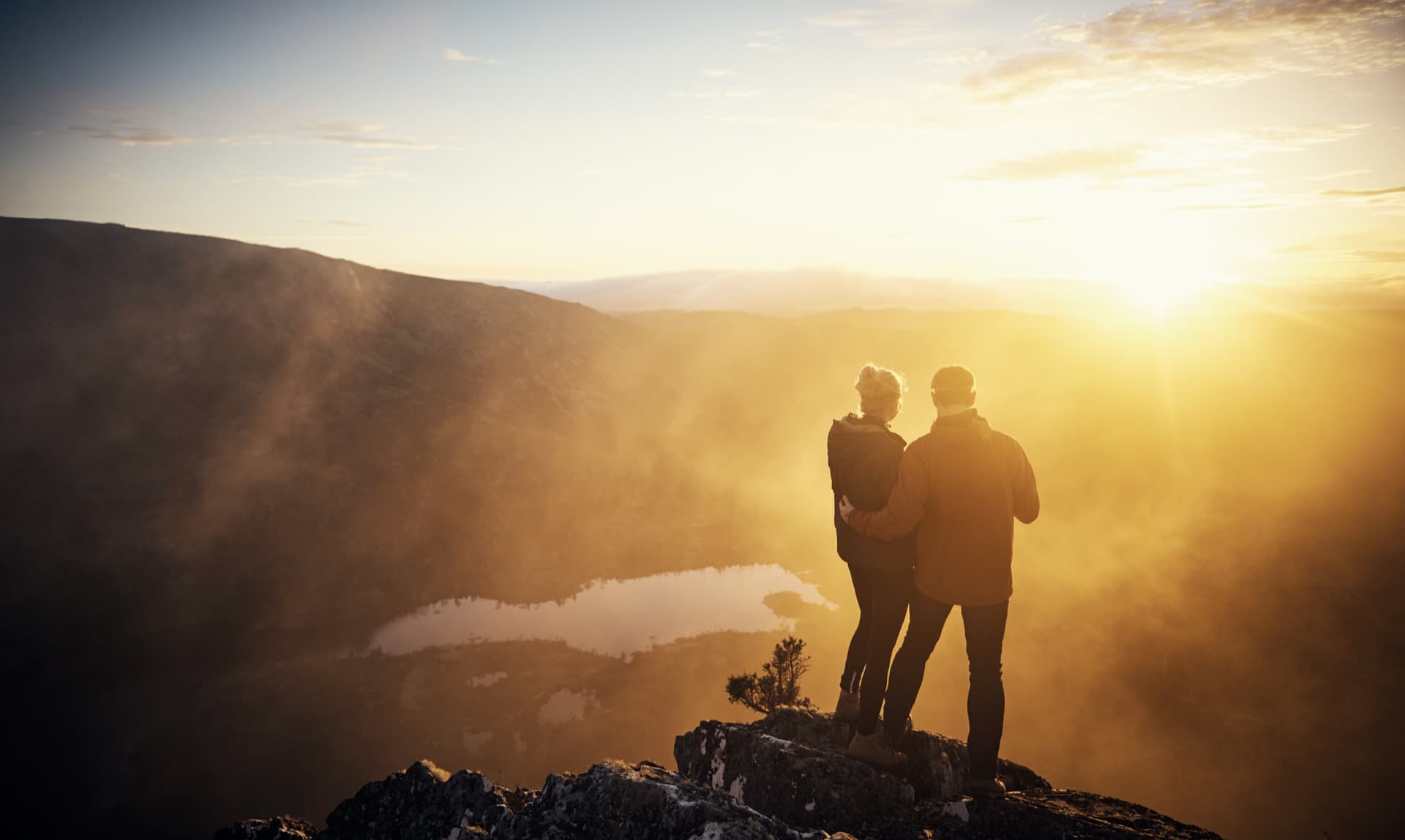 Couple standing on mountain summit at sunset overlooking Blue Ridge Mountains